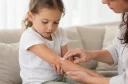Otrok z atopijskim dermatitisom na roki med nanosom negovalne kreme